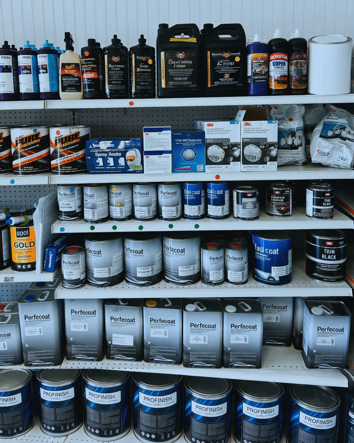 Collection of automotive refinishing products on display, including spray paints, primers, clear coats, and coatings from brands like SEM, Advantage, ProXL, Master Service, HiQ, and Perfecoat.